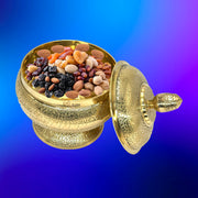 Decorative gold container filled with dried fruits on a blue gradient background