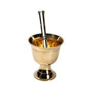 Three brass mortars with pestles in different sizes, featuring a gold finish, displayed on a wooden countertop with a blurred kitchen background.