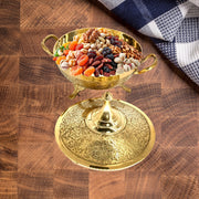 Decorative gold bowl filled with dried fruits on a wooden surface