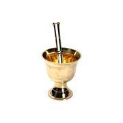 Three brass mortars with pestles in different sizes, featuring a gold finish, displayed on a wooden countertop with a blurred kitchen background.